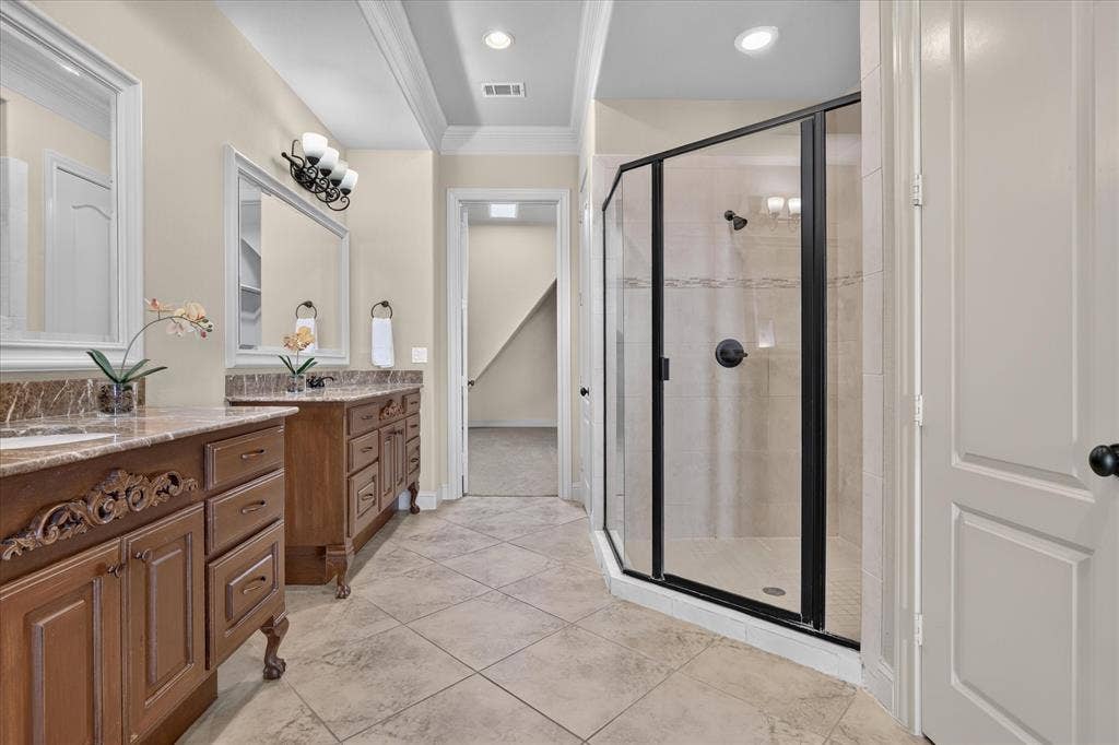 563 Rockingham Drive, Irving, TX 75063 Dual wood cabinetry with stone-finish countertops, ceramic tile flooring, and a walk-in shower featuring a black-framed glass enclosure