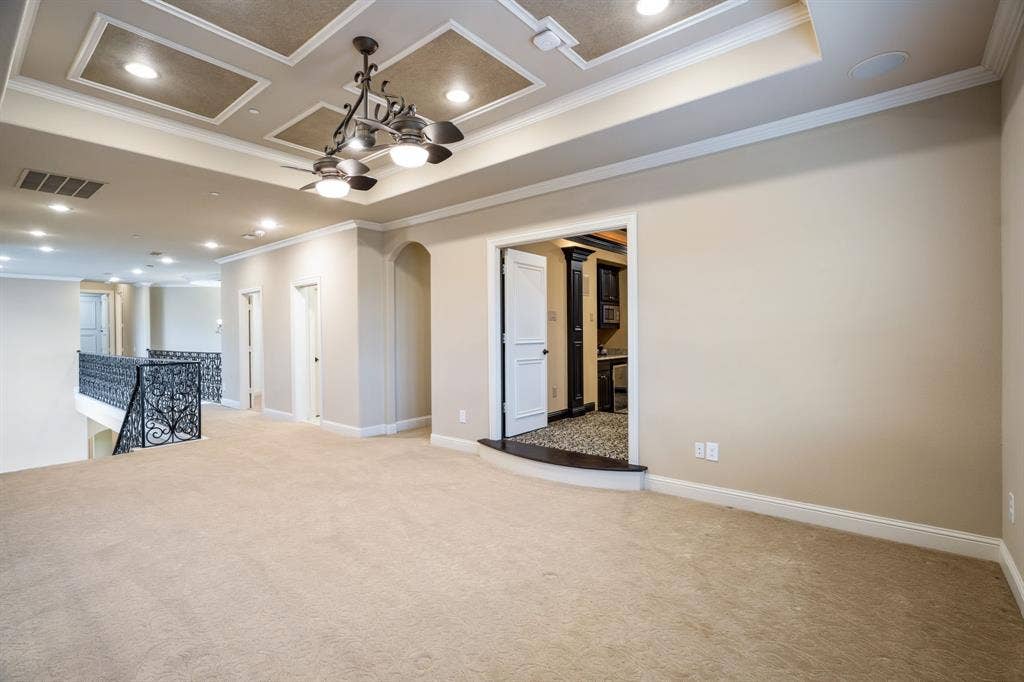 6590 Gerrard Street, Frisco, TX 75034 Tray ceiling with recessed lighting, wrought-iron balustrade, and multi-light chandelier fixture