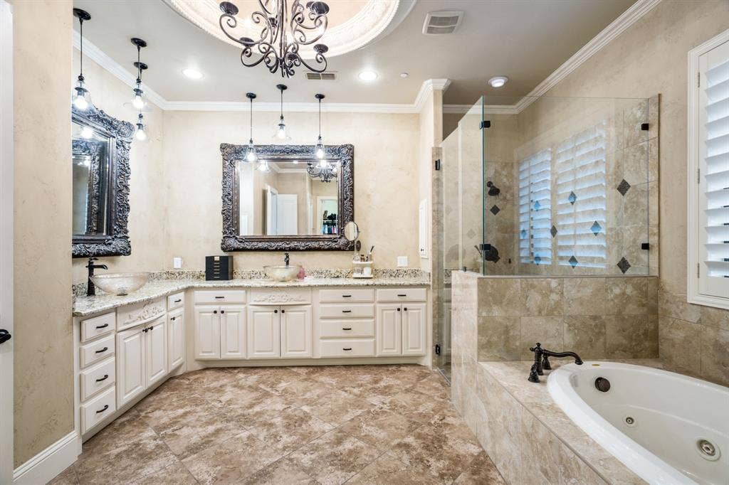 6590 Gerrard Street, Frisco, TX 75034 Bathroom featuring a double vanity with stone countertops and glass vessel sinks, stone tile flooring, a jetted soaking tub, and a glass-enclosed shower with stone tile surround