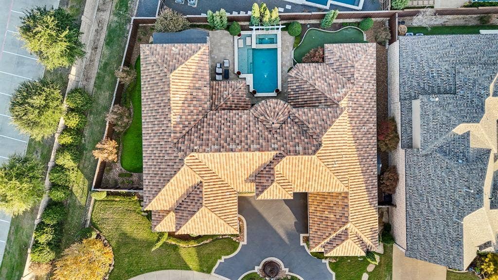 6590 Gerrard Street, Frisco, TX 75034 Aerial perspective of a multi-gabled tile roof residence featuring a swimming pool, attached spa, putting green, and stone-surfaced patio area