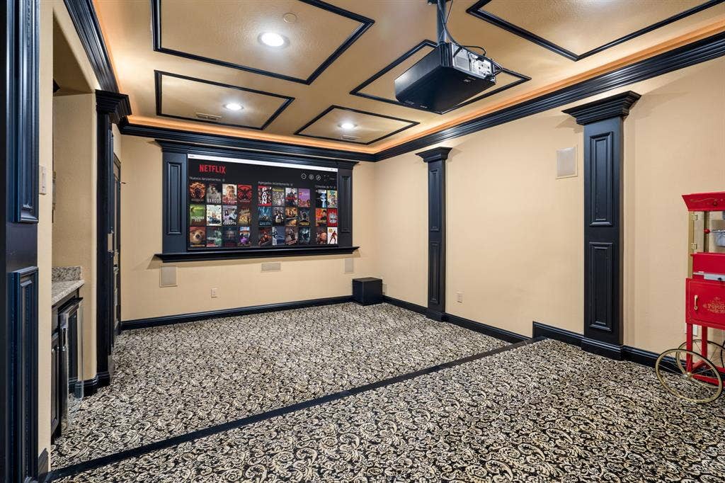 6590 Gerrard Street, Frisco, TX 75034 Dedicated media room featuring a coffered ceiling, recessed lighting, built-in display cabinetry, decorative columns, and a fixed projector mount