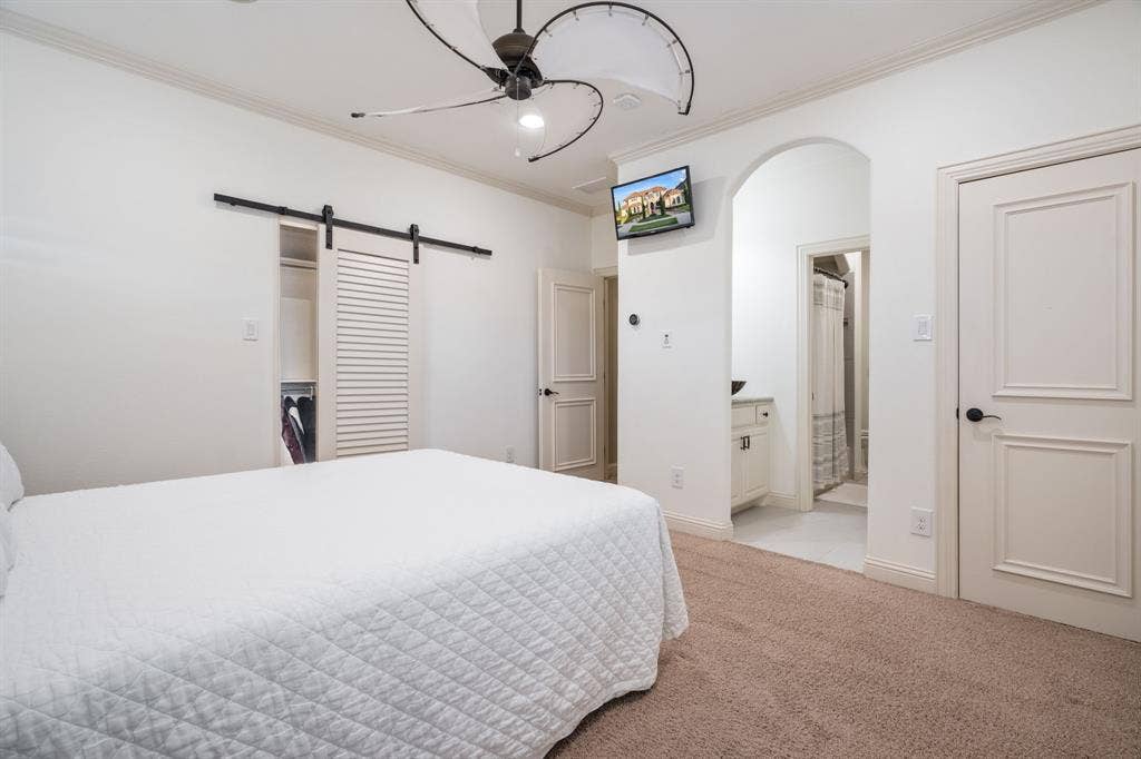 6590 Gerrard Street, Frisco, TX 75034 Sliding barn door featuring a matte black track system, arched entryway, multi-panel interior doors, and a contemporary ceiling fan