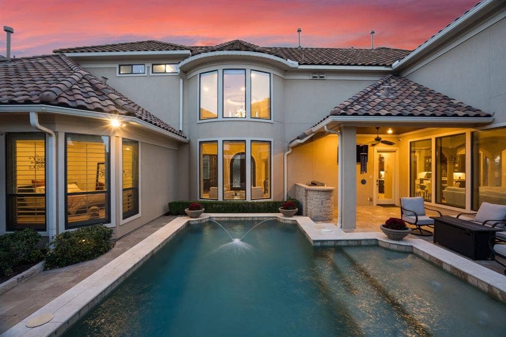 6590 Gerrard Street, Frisco, TX 75034 Stucco exterior featuring a multi-gabled tile roof, swimming pool with integrated fountain feature, stone-finished outdoor kitchen, and covered patio area with recessed lighting