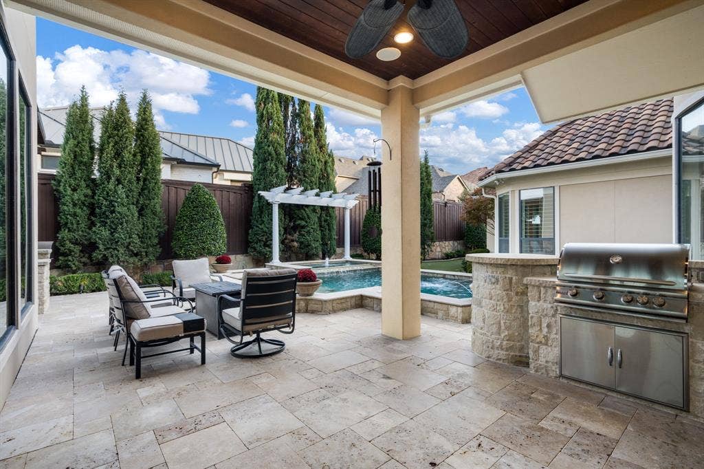 6590 Gerrard Street, Frisco, TX 75034 Covered patio featuring stone tile flooring, a wood-paneled ceiling, a built-in stainless steel outdoor grill, and a swimming pool with a pergola