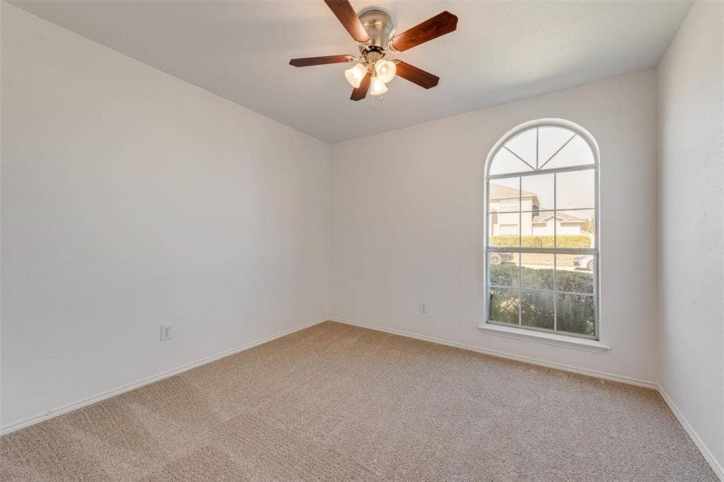 412 Overland Trail, Cedar Hill, TX 75104 Neutral-toned wall finish, wall-to-wall carpeting, arched window with a grid pattern, and a ceiling-mounted fan with integrated lighting