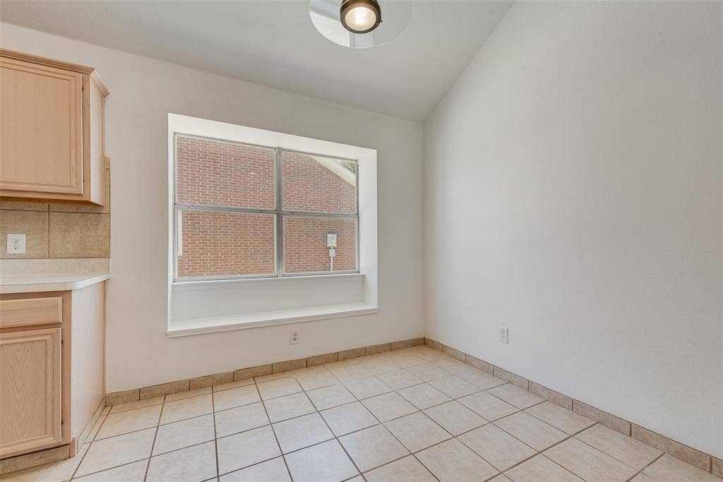 412 Overland Trail, Cedar Hill, TX 75104 Vaulted ceiling, inset window with a built-in sill, light-toned wood cabinetry, and ceramic tile flooring