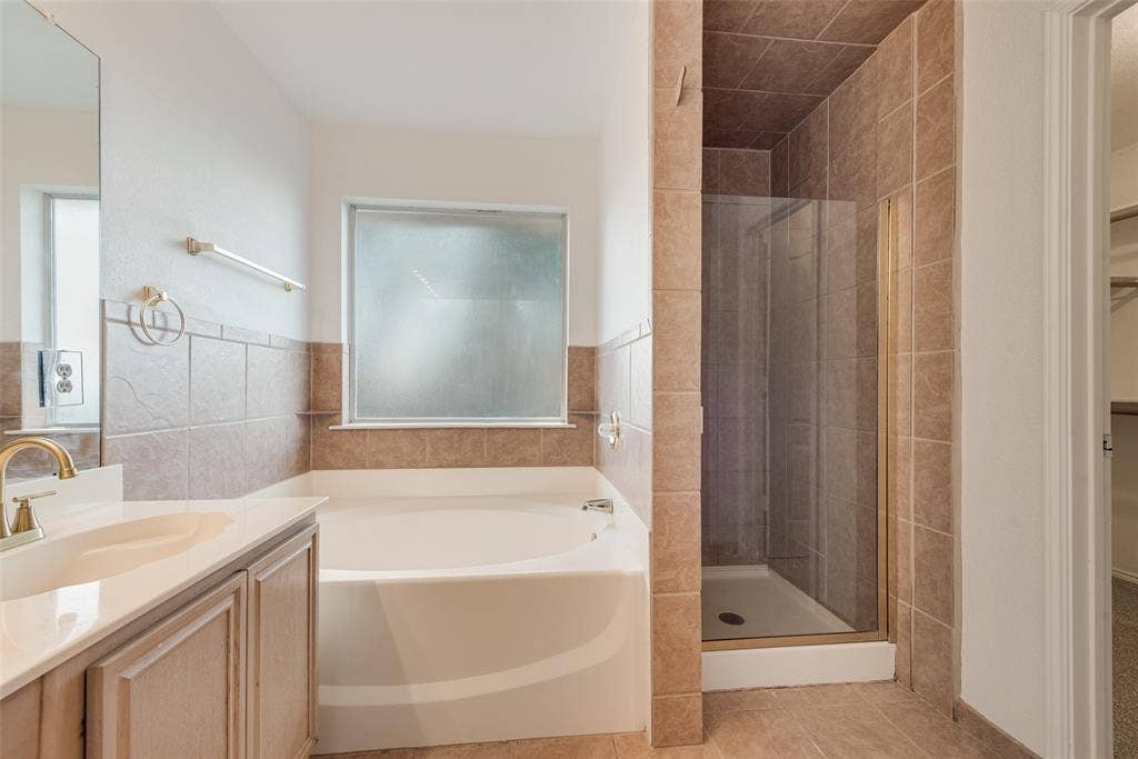 412 Overland Trail, Cedar Hill, TX 75104 Bathroom featuring a soaking tub, separate tiled shower enclosure with glass door, vanity with a rectangular basin, and neutral-toned wall tiling