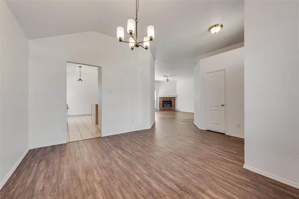 412 Overland Trail, Cedar Hill, TX 75104 Open dining area featuring vaulted ceilings, wood-finish flooring, a multi-arm chandelier, and a masonry fireplace
