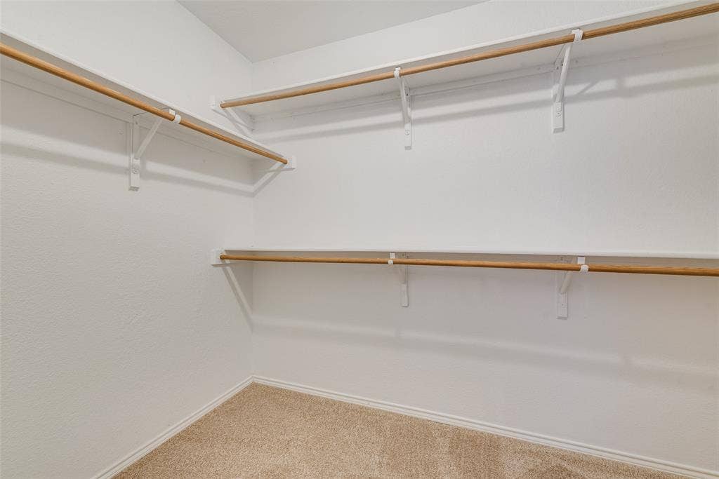 412 Overland Trail, Cedar Hill, TX 75104 Walk-in storage space featuring multi-level white shelving and integrated wooden garment rods, complemented by wall-to-wall carpeting