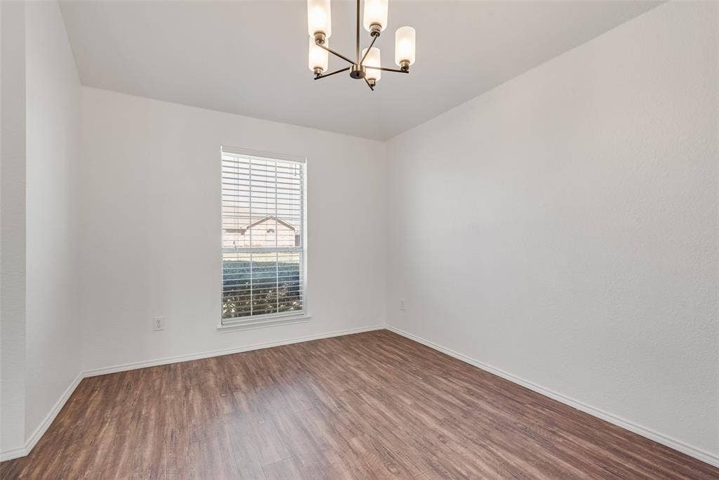412 Overland Trail, Cedar Hill, TX 75104 Room featuring wood-finish flooring, a neutral color palette, a single window with horizontal blinds, and a five-light tiered chandelier with a metallic finish