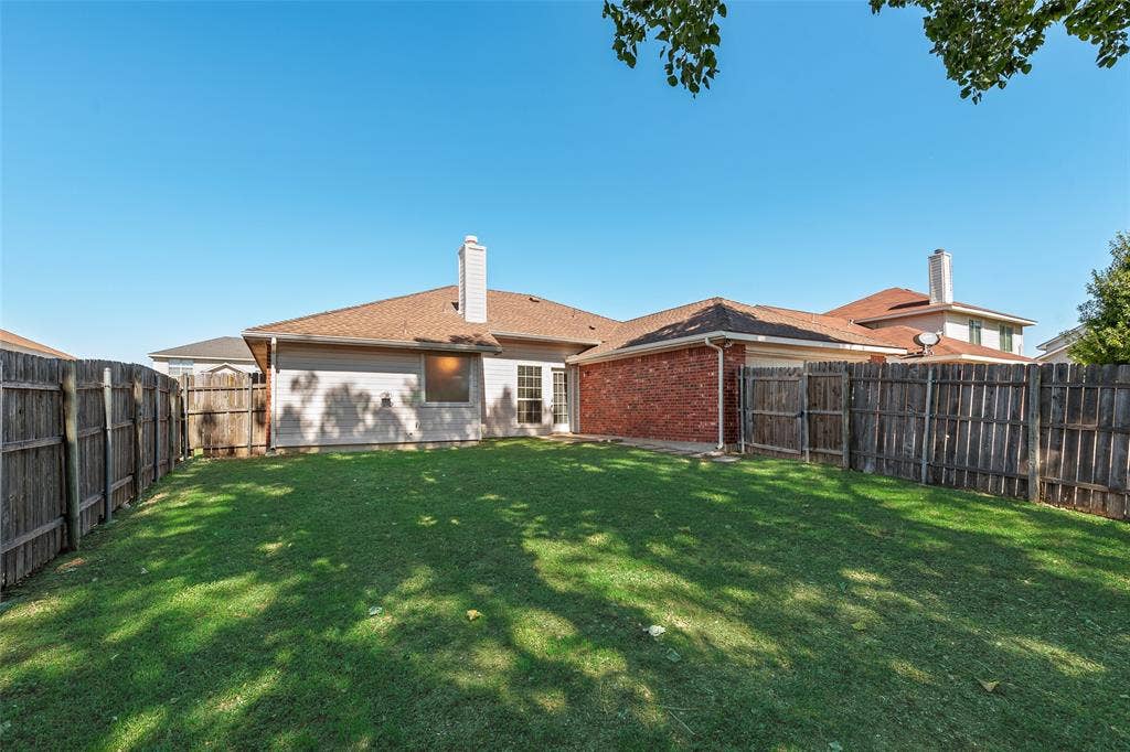 412 Overland Trail, Cedar Hill, TX 75104 Backyard featuring a grass lawn, perimeter wood fencing, masonry chimney, and brick exterior accents