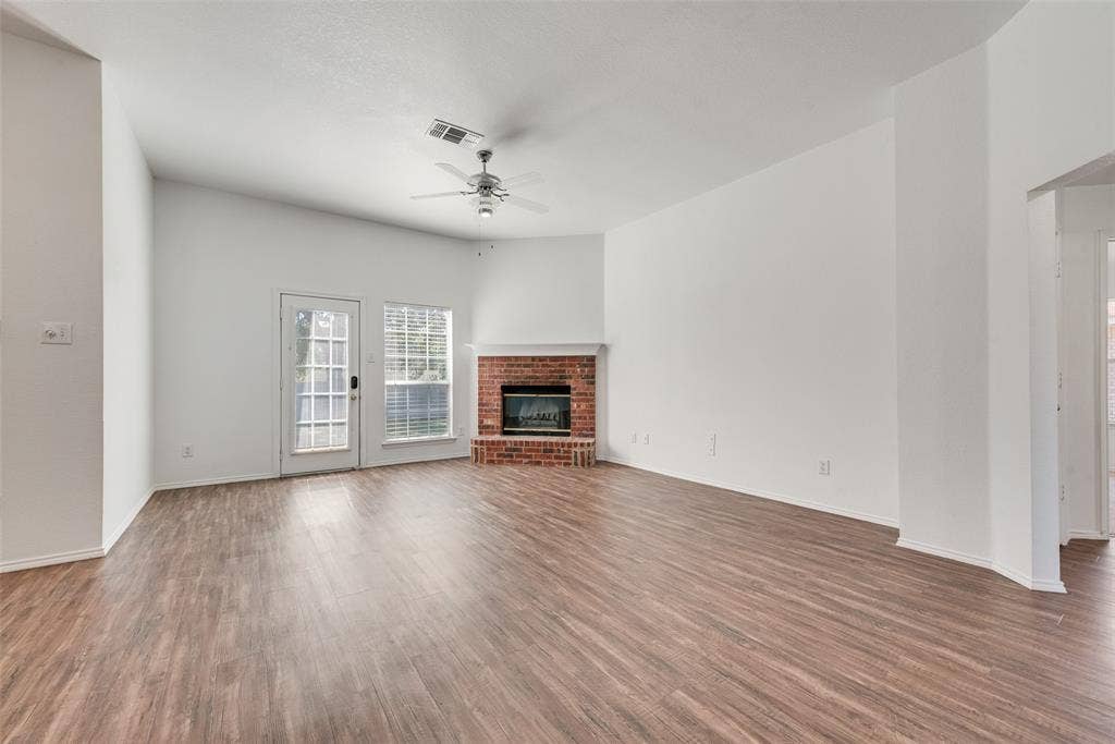 412 Overland Trail, Cedar Hill, TX 75104 Living area featuring wood-finish flooring, vaulted ceilings, brick fireplace with mantel, ceiling fan, and access to the exterior