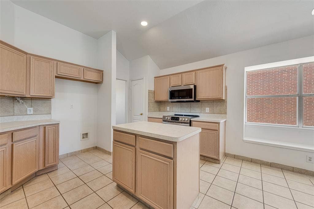 412 Overland Trail, Cedar Hill, TX 75104 Kitchen featuring light-finish cabinetry, a center island with a solid surface countertop, ceramic tile flooring, built-in stainless steel microwave, and a recessed window ledge