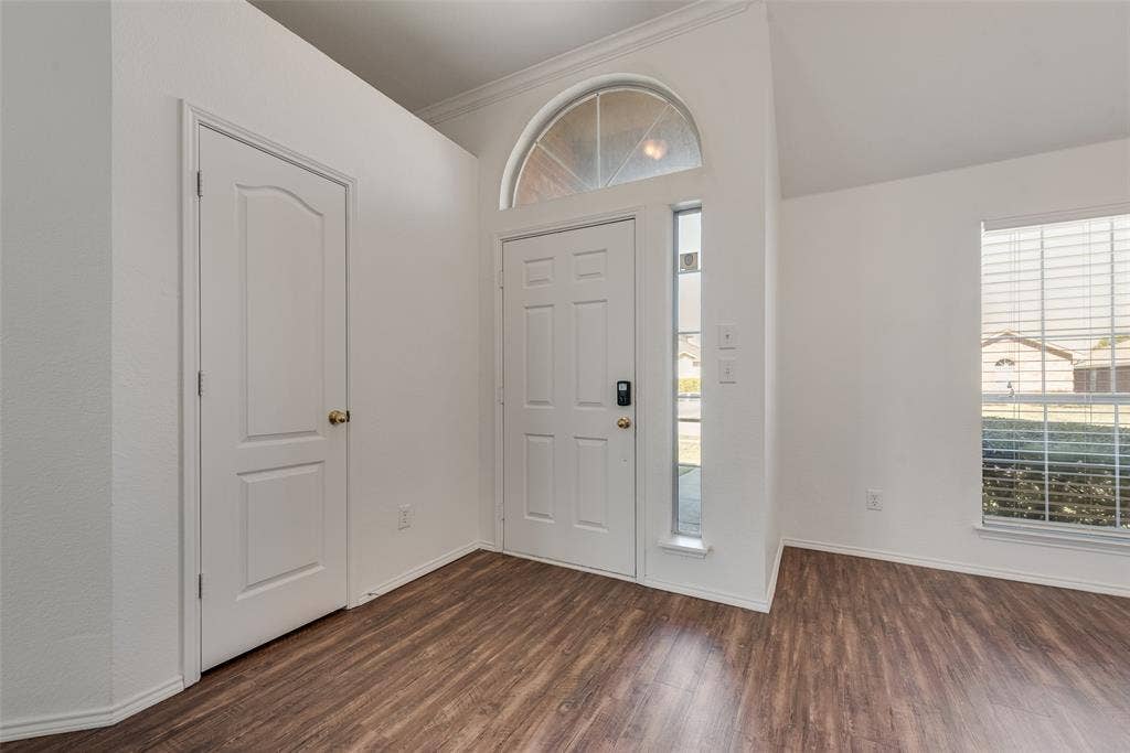 412 Overland Trail, Cedar Hill, TX 75104 Entryway featuring wood-finish flooring, vaulted ceilings, a six-panel front door with an arched transom window, a vertical sidelight, and a large window with blinds
