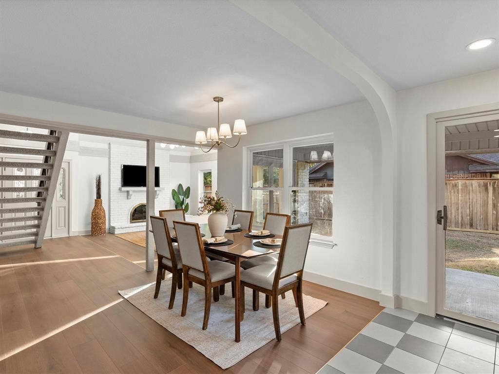 Dining area featuring wood-finish flooring, arched architectural detailing, a multi-light chandelier, and a glass-paned sliding door