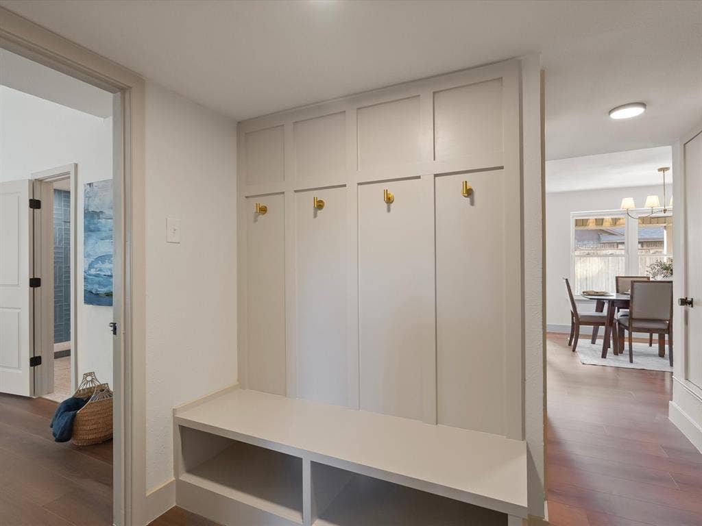 Built-in mudroom cabinetry featuring custom millwork, integrated bench seating, open cubby storage, and metallic wall-mounted hooks