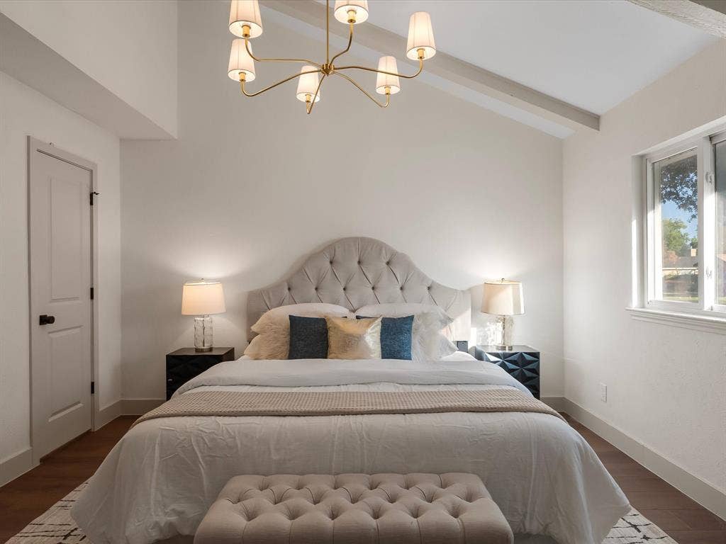 Vaulted ceilings, wood-finish flooring, and multi-arm chandelier with cream fabric shades