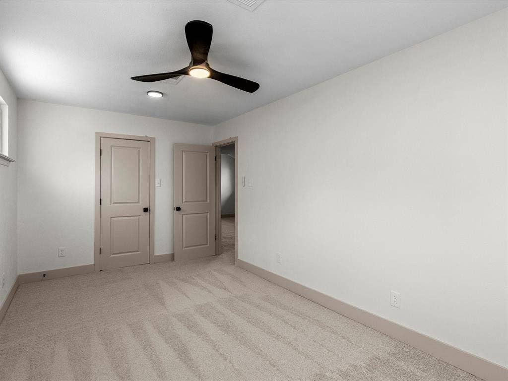 Neutral interior featuring wall-to-wall carpeting, three-blade ceiling fan with integrated lighting, and two-panel interior doors