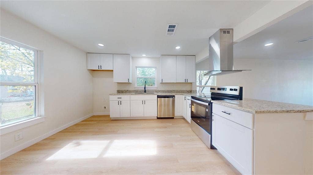 3901 Park Street, Greenville, TX 75401 Kitchen featuring white shaker-style cabinetry, stone-finish countertops, stainless steel appliances, a stainless steel range hood, and wood-finish flooring