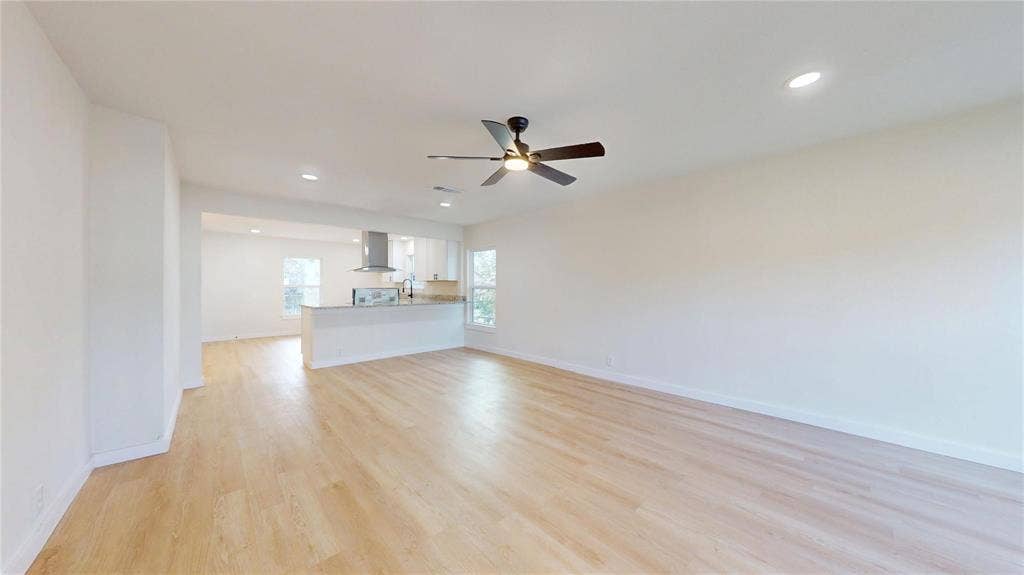 3901 Park Street, Greenville, TX 75401 Open-concept area featuring light-tone wood-finish flooring, recessed lighting, a ceiling fan with integrated light, and a kitchen peninsula with cabinetry