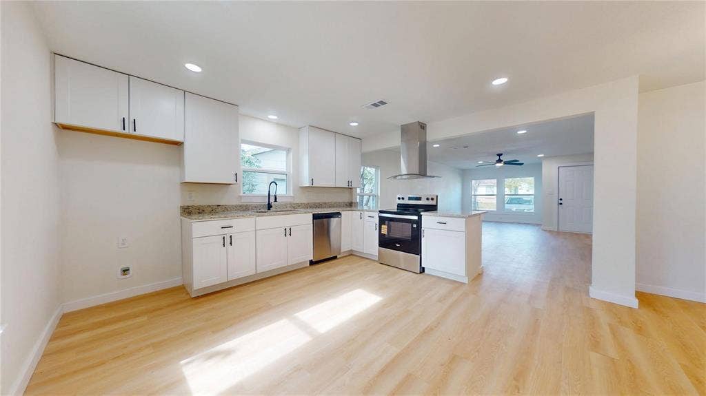 3901 Park Street, Greenville, TX 75401 Kitchen featuring white cabinetry, stone countertops, stainless steel appliances, a stainless steel chimney-style range hood, and wood-finish flooring