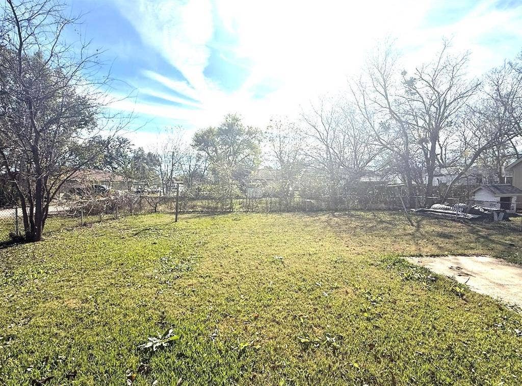 3901 Park Street, Greenville, TX 75401 Open backyard featuring a chain-link perimeter fence, concrete slab, and mature trees