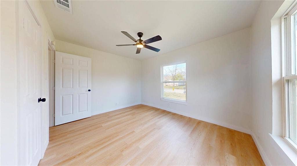 3901 Park Street, Greenville, TX 75401 Neutral-toned room featuring wood-finish flooring, a ceiling fan with integrated lighting, dual-panel interior doors, and multiple windows