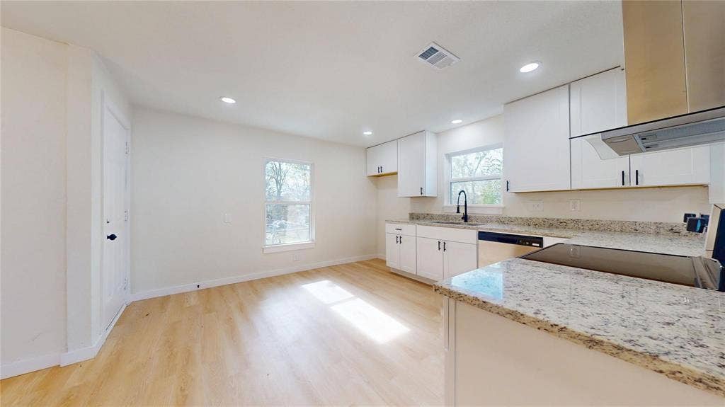 3901 Park Street, Greenville, TX 75401 Kitchen featuring white shaker-style cabinetry, stone countertops, integrated stainless steel appliances, a matte black faucet, and wood-finish flooring