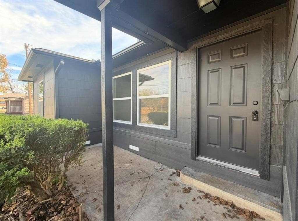 3901 Park Street, Greenville, TX 75401 Covered porch entry featuring dark exterior siding, six-panel door, and dual-pane windows