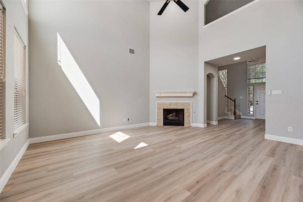1716 Clarke Springs Drive, Allen, TX 75002 Two-story living area featuring wood-finish flooring, vaulted ceilings, a fireplace with a mantel, and a ceiling fan