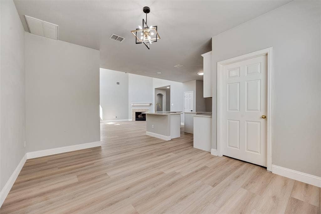 1716 Clarke Springs Drive, Allen, TX 75002 Interior space featuring wood-finish flooring, a geometric pendant light fixture, a neutral color palette, a kitchen island, and a fireplace