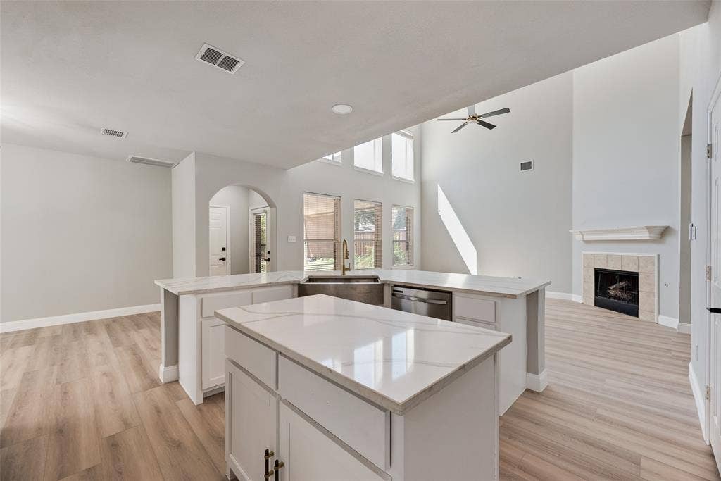 1716 Clarke Springs Drive, Allen, TX 75002 Kitchen featuring a central island with a stone-finish countertop, stainless steel undermount sink, white cabinetry, and wood-finish flooring