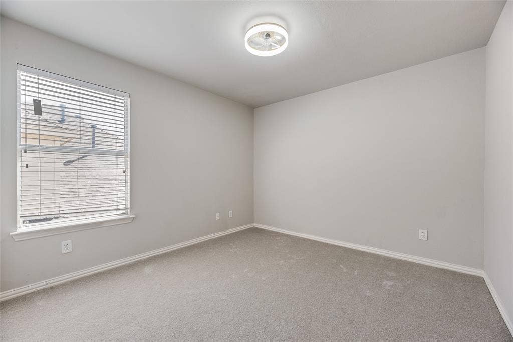 1716 Clarke Springs Drive, Allen, TX 75002 Neutral-toned interior space featuring wall-to-wall carpeting, a single-pane window with horizontal blinds, and a circular LED flush-mount ceiling fixture
