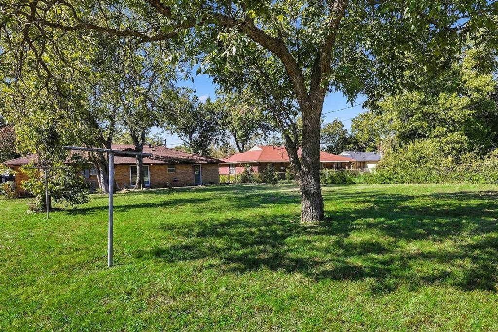 2810 Bonnie View Road, Dallas, TX 75216 Expansive backyard featuring a sprawling lawn, mature trees, and perimeter fencing