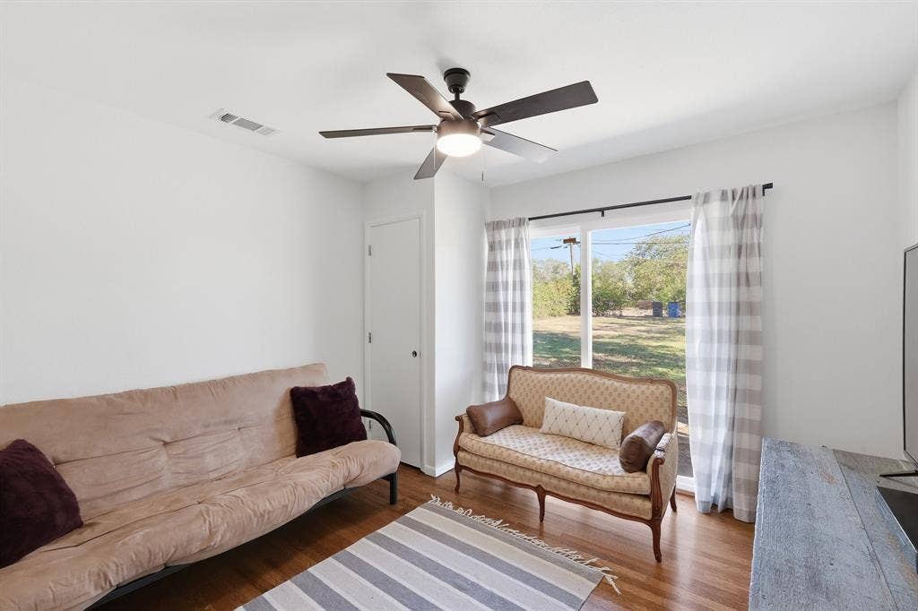 2810 Bonnie View Road, Dallas, TX 75216 Interior room featuring wood-finish flooring, a ceiling-mounted light fixture with fan blades, and a large window