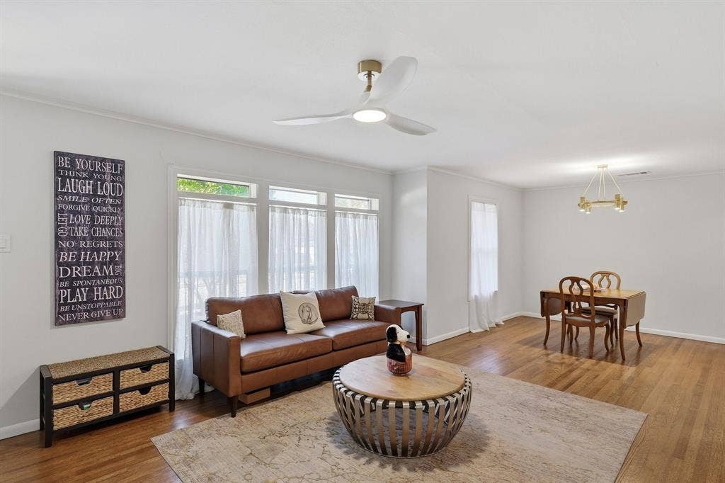 2810 Bonnie View Road, Dallas, TX 75216 Open-concept interior featuring wood-finish flooring, triple-pane window configuration, integrated ceiling fan with light, and modern tiered chandelier