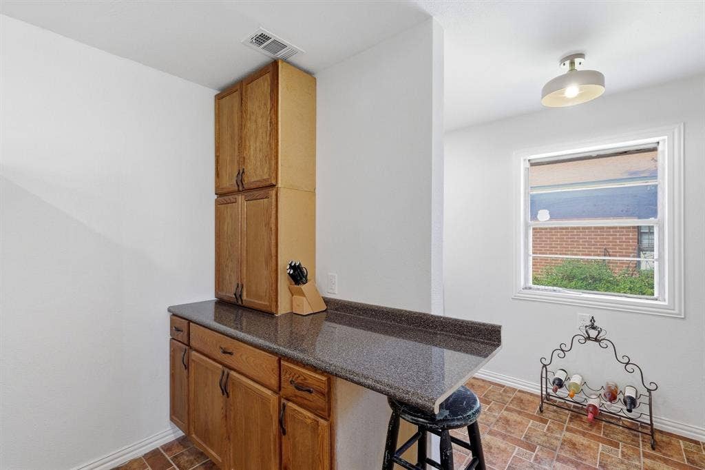 2810 Bonnie View Road, Dallas, TX 75216 Built-in wood cabinetry with stone-surface countertop, tile flooring, and overhead dome lighting