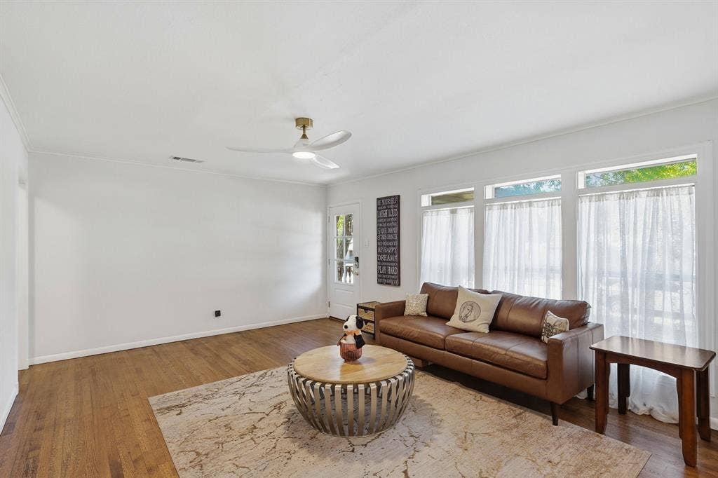 2810 Bonnie View Road, Dallas, TX 75216 Wood-finish flooring, white walls, and a ceiling-mounted light fixture with fan blades, complemented by a series of windows