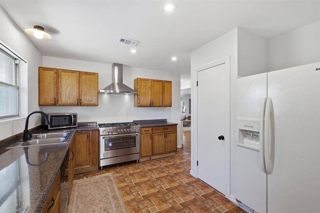 2810 Bonnie View Road, Dallas, TX 75216 Kitchen featuring wood cabinetry, stone-surface countertops, stainless steel range with matching ventilation hood, and recessed lighting