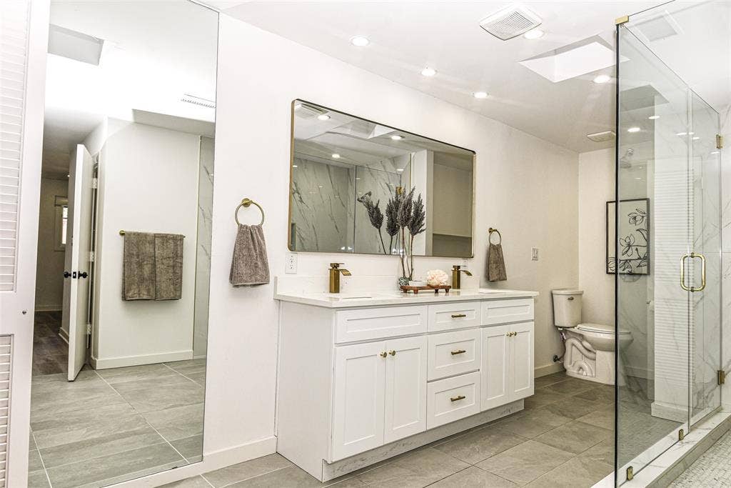 13936 Tanglewood Place, Farmers Branch, TX 75234 Luxury and beauty with this white vanity with integrated countertop, dual metal faucets, large framed wall mirror, glass-enclosed shower, and tile flooring