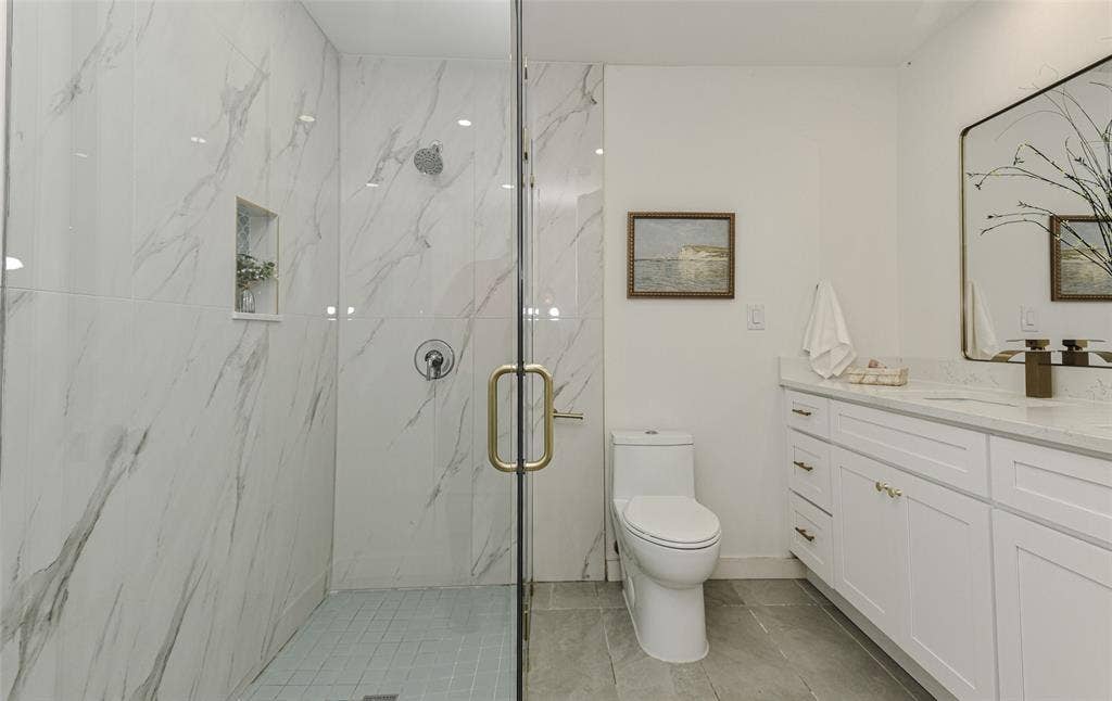 13936 Tanglewood Place, Farmers Branch, TX 75234 The Walk-in glass-enclosed shower has wall-mounted shower head and integrated recessed niche