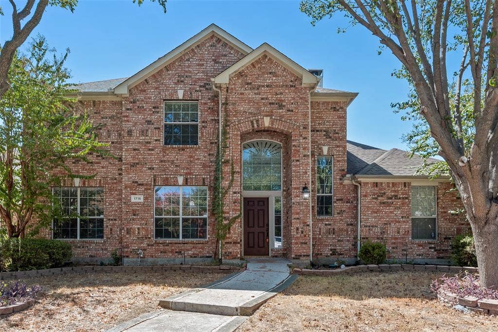 1716 Clarke Springs Drive, Allen, TX 75002 Two-story brick exterior featuring a multi-gabled roofline, an arched entryway with a transom window, and stone hardscaping borders