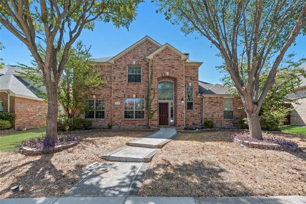 1716 Clarke Springs Drive, Allen, TX 75002 Two-story brick exterior featuring an arched entryway, decorative stone-bordered landscaping, and a concrete walkway