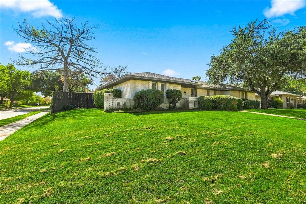 1900 Ports O Call Drive, Plano, TX 75075 Single-story residence featuring a light-toned brick facade, low-profile roofline, mature landscaping, and a fenced side yard