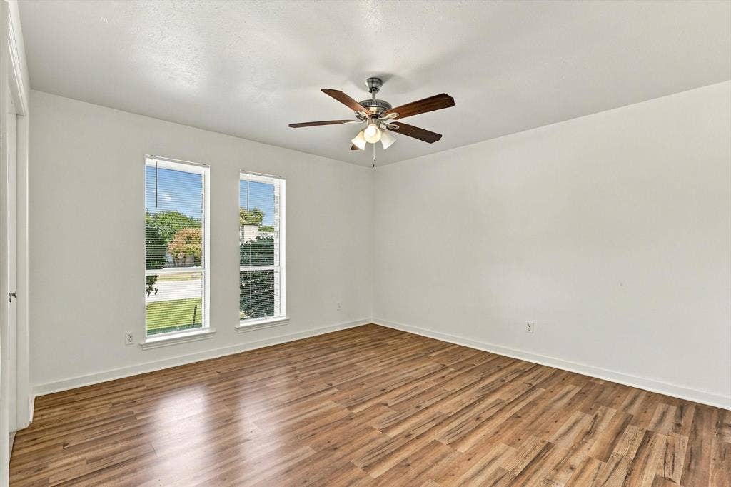 1900 Ports O Call Drive, Plano, TX 75075 Interior room featuring wood-finish flooring, dual vertical windows, and a ceiling fan with integrated lighting