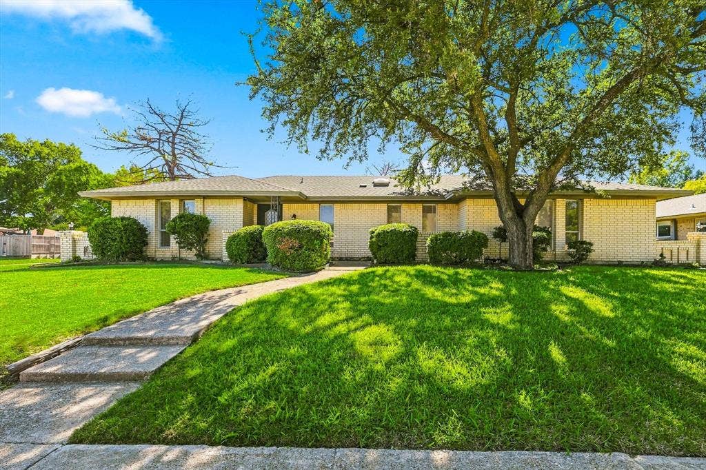 1900 Ports O Call Drive, Plano, TX 75075 Single-story residence with a light-colored brick exterior, hip roof, concrete walkway, and mature landscaping