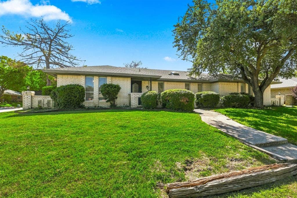 1900 Ports O Call Drive, Plano, TX 75075 Single-story brick exterior featuring a low-slope roof, concrete walkway, and mature landscaping