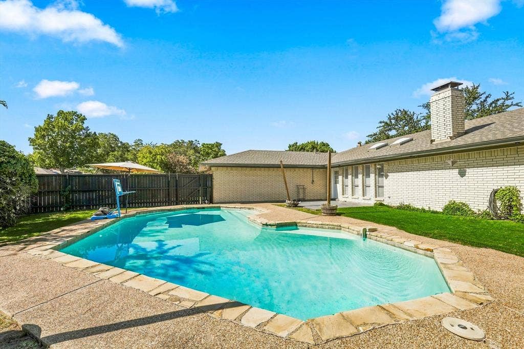 1900 Ports O Call Drive, Plano, TX 75075 Backyard featuring an in-ground swimming pool, flagstone coping, aggregate concrete decking, perimeter wood fencing, and brick exterior walls