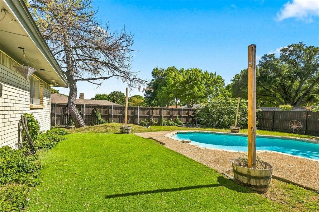 1900 Ports O Call Drive, Plano, TX 75075 Backyard featuring a swimming pool, aggregate concrete decking, manicured lawn, perimeter wood fencing, and mature trees