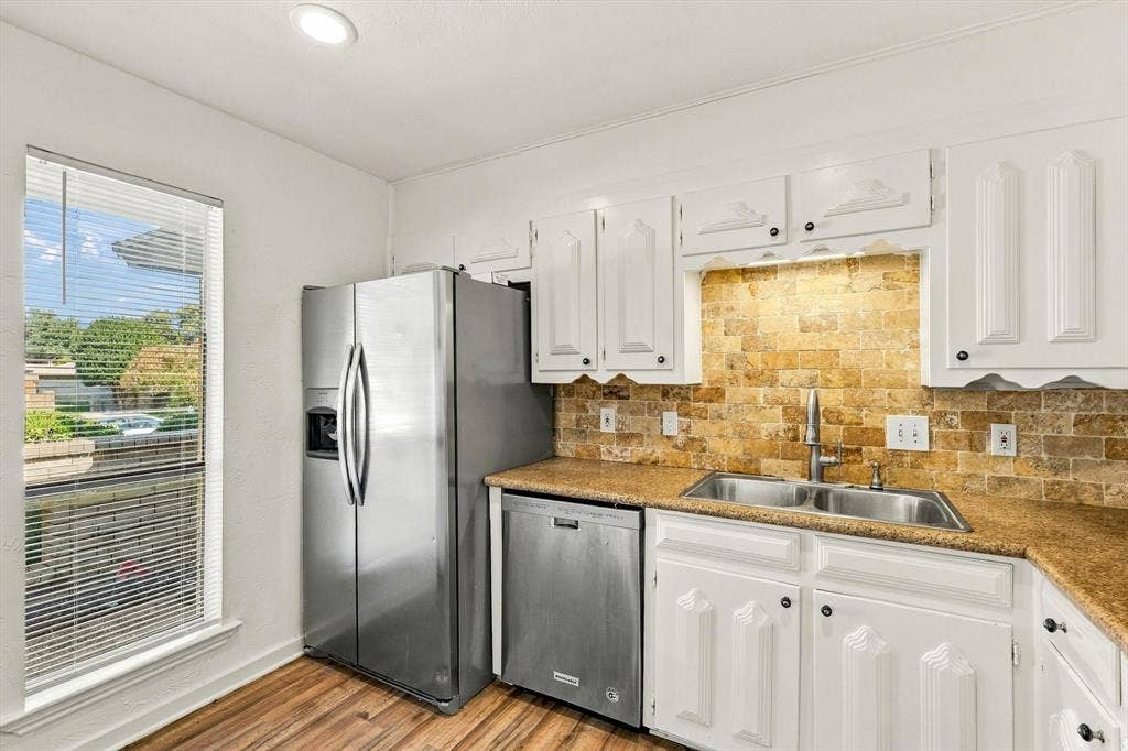 1900 Ports O Call Drive, Plano, TX 75075 Kitchen featuring white cabinetry, stainless steel appliances, natural stone tile backsplash, wood-finish flooring, and recessed lighting